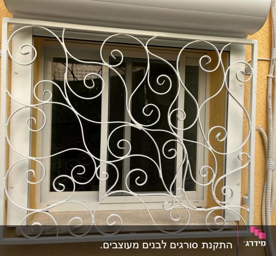 סורגי מתכת לבנים עם עיטורים מעוגלים על חלון